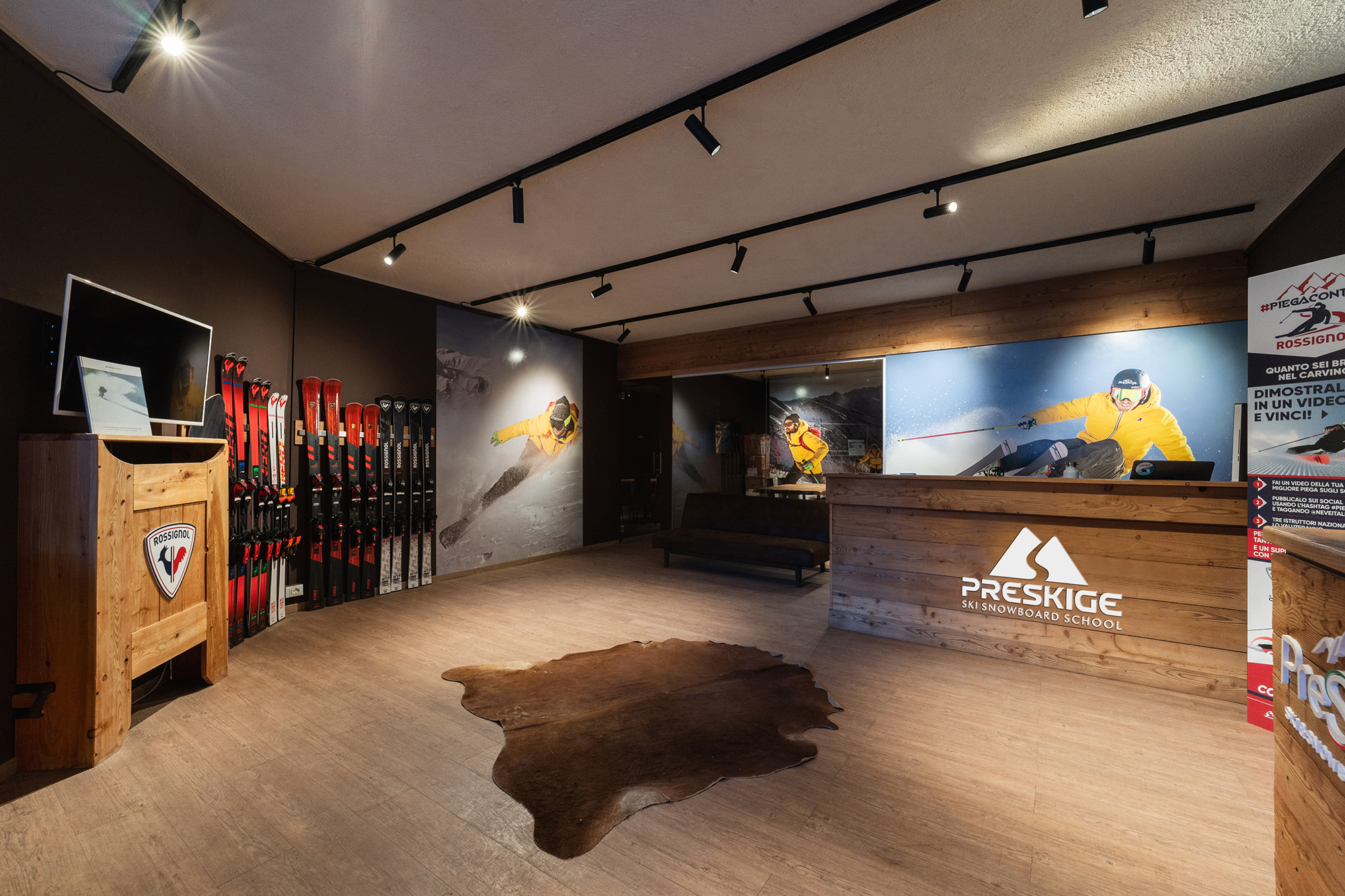 Interno della sede Preskige a Sestriere: rastrelliere di sci, bancone e logo illuminato