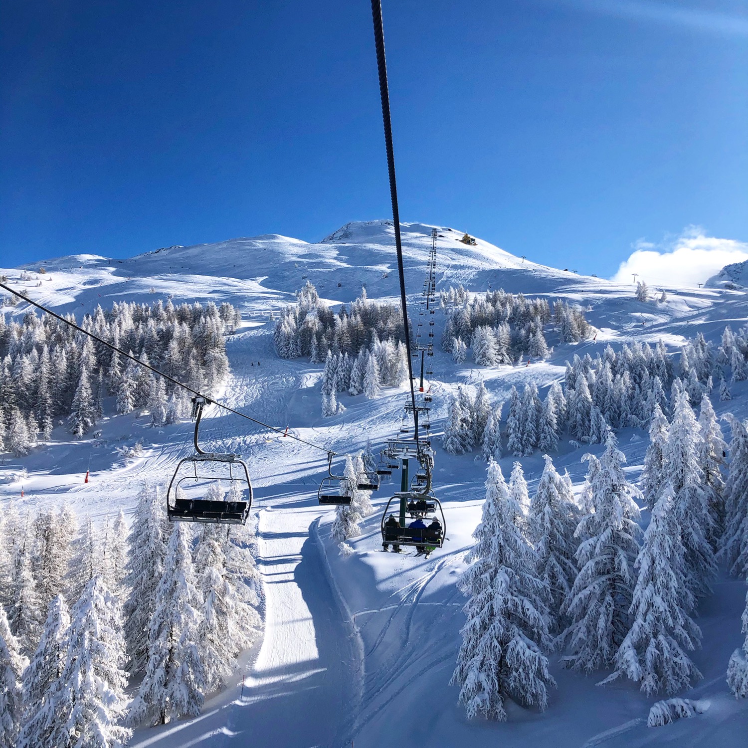 Seggiovia che sale tra i larici innevati verso le piste alte della Via Lattea